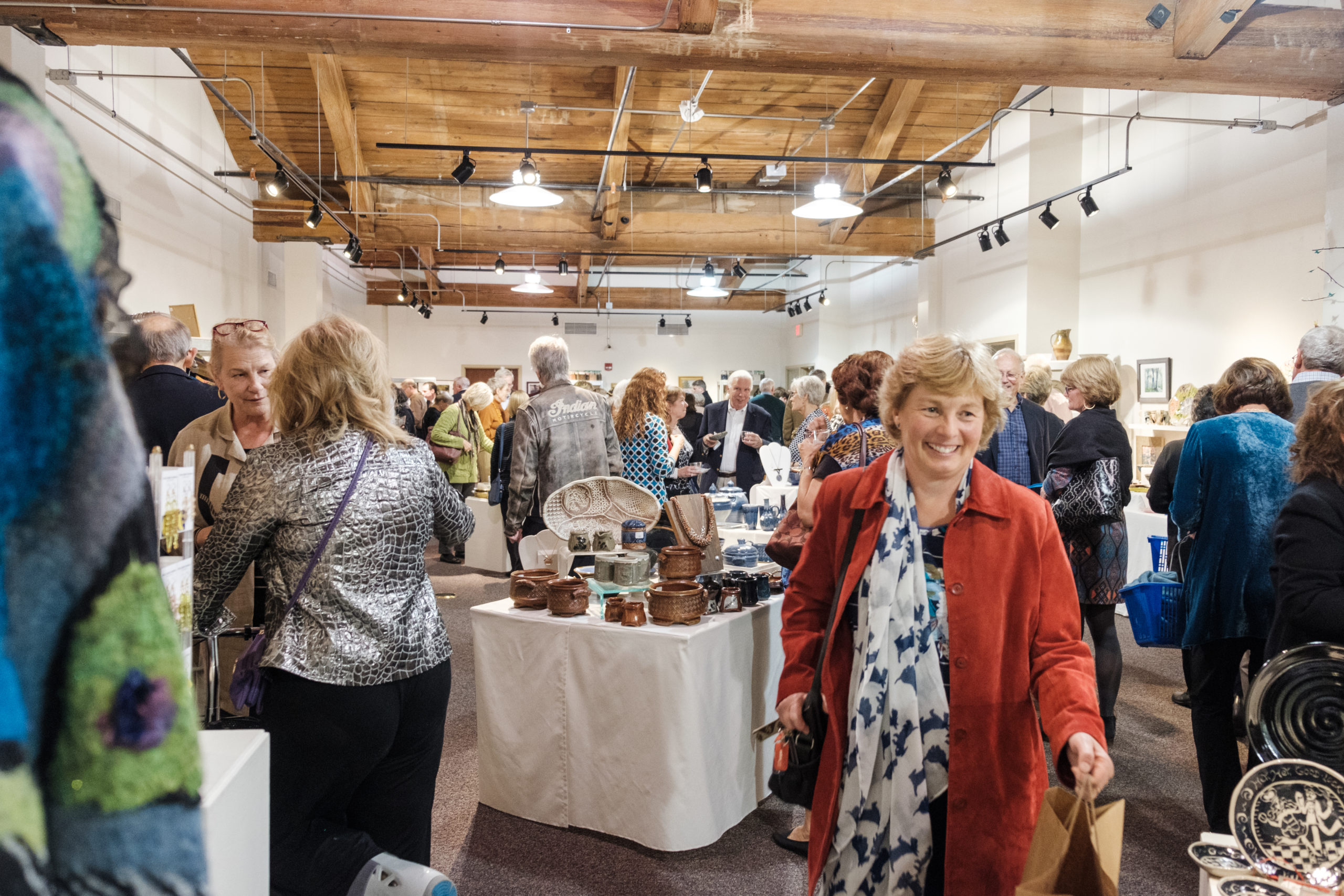 A crowd of shoppers in Sawtooth's gallery space, browsing tables of handcrafted goods.